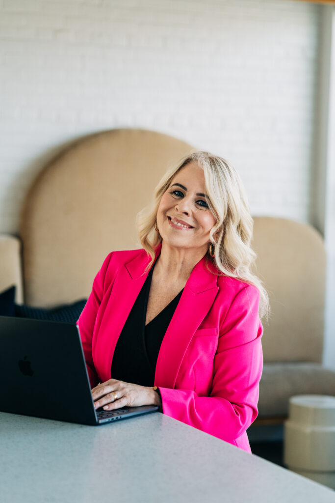 Jo Leda Martin Christian Counselor using laptop, smiling at camera